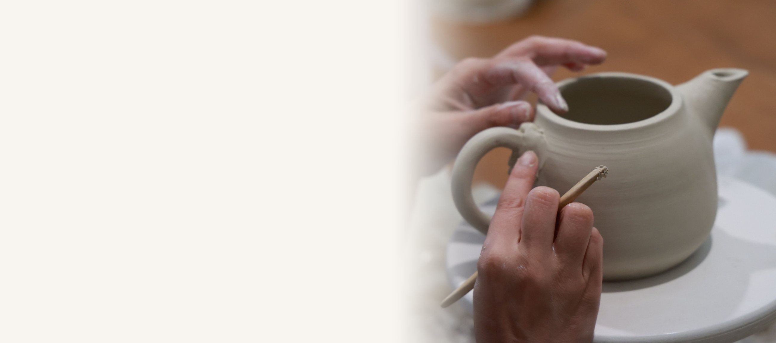 Mains qui finissent une théière en terre pendant un cours de céramique à l’atelier
