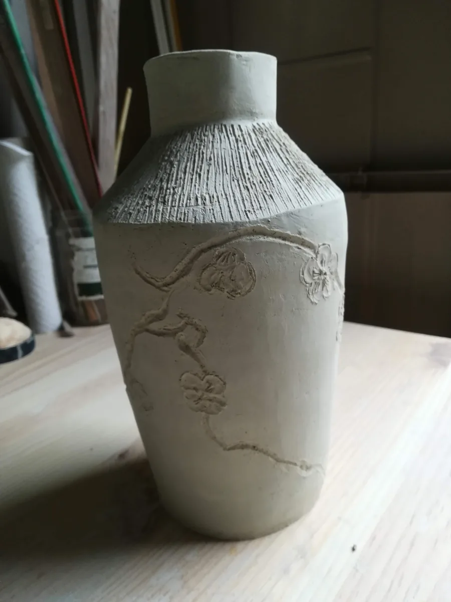 Vase en terre encore brute, travaillé et décoré de motifs végétaux à l’atelier